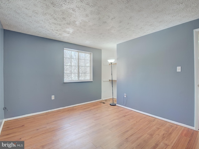 empty room featuring wood-type flooring and a textured ceiling