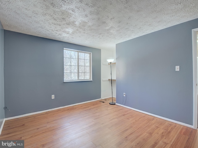 spare room featuring hardwood / wood-style flooring and a textured ceiling