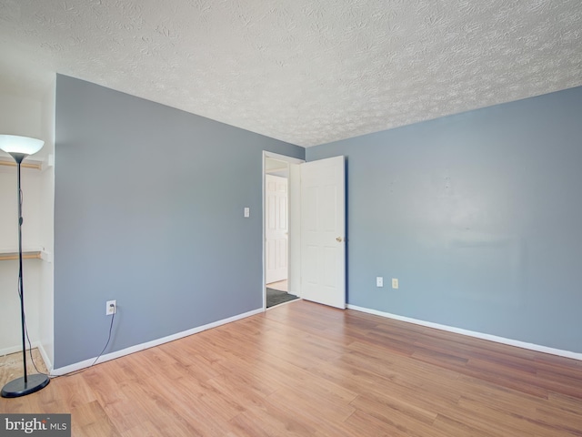 spare room featuring hardwood / wood-style floors and a textured ceiling