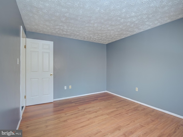 empty room featuring a textured ceiling and light hardwood / wood-style flooring