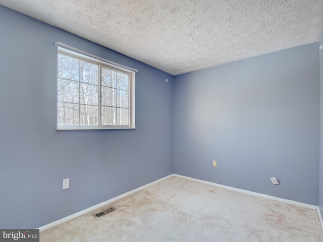 carpeted spare room with a textured ceiling