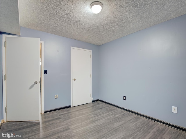 spare room featuring a textured ceiling and light hardwood / wood-style flooring