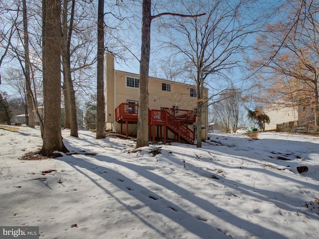 snow covered back of property with a wooden deck