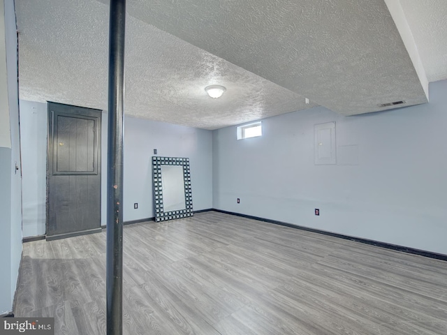 basement with light hardwood / wood-style floors and a textured ceiling