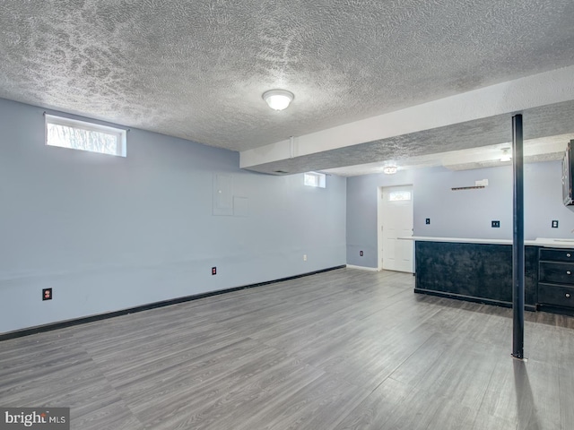 basement featuring light hardwood / wood-style floors and a textured ceiling