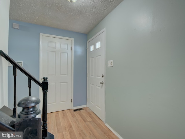 foyer entrance featuring a textured ceiling and light wood-type flooring