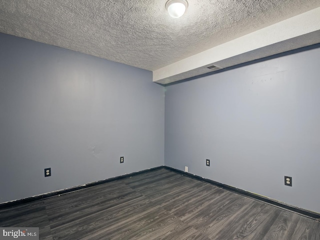 spare room featuring dark hardwood / wood-style flooring and a textured ceiling