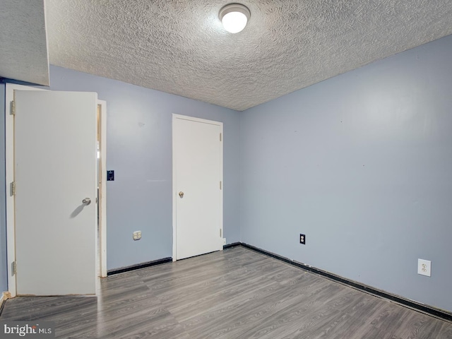 spare room with a textured ceiling and light wood-type flooring