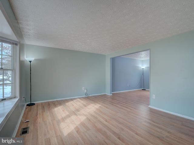 unfurnished room featuring light wood-type flooring and a textured ceiling