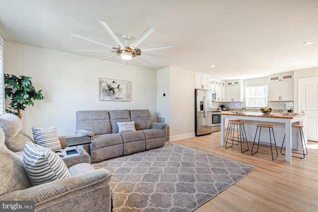 living area with a ceiling fan, visible vents, baseboards, light wood-style flooring, and recessed lighting