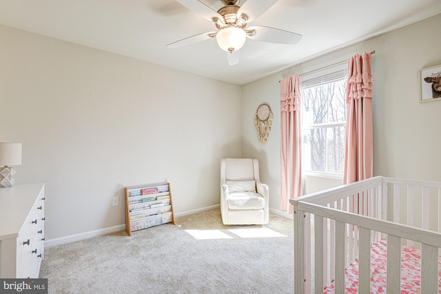 bedroom featuring a nursery area, carpet, baseboards, and ceiling fan