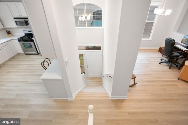 interior space with an inviting chandelier, plenty of natural light, and light wood-type flooring