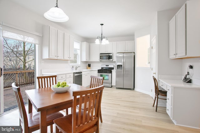 dining area with sink, a notable chandelier, and light hardwood / wood-style flooring