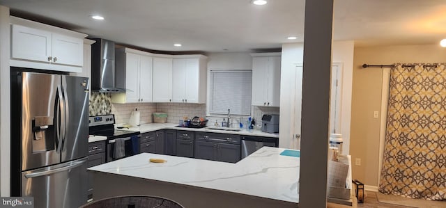 kitchen featuring gray cabinets, appliances with stainless steel finishes, white cabinetry, light stone counters, and wall chimney exhaust hood