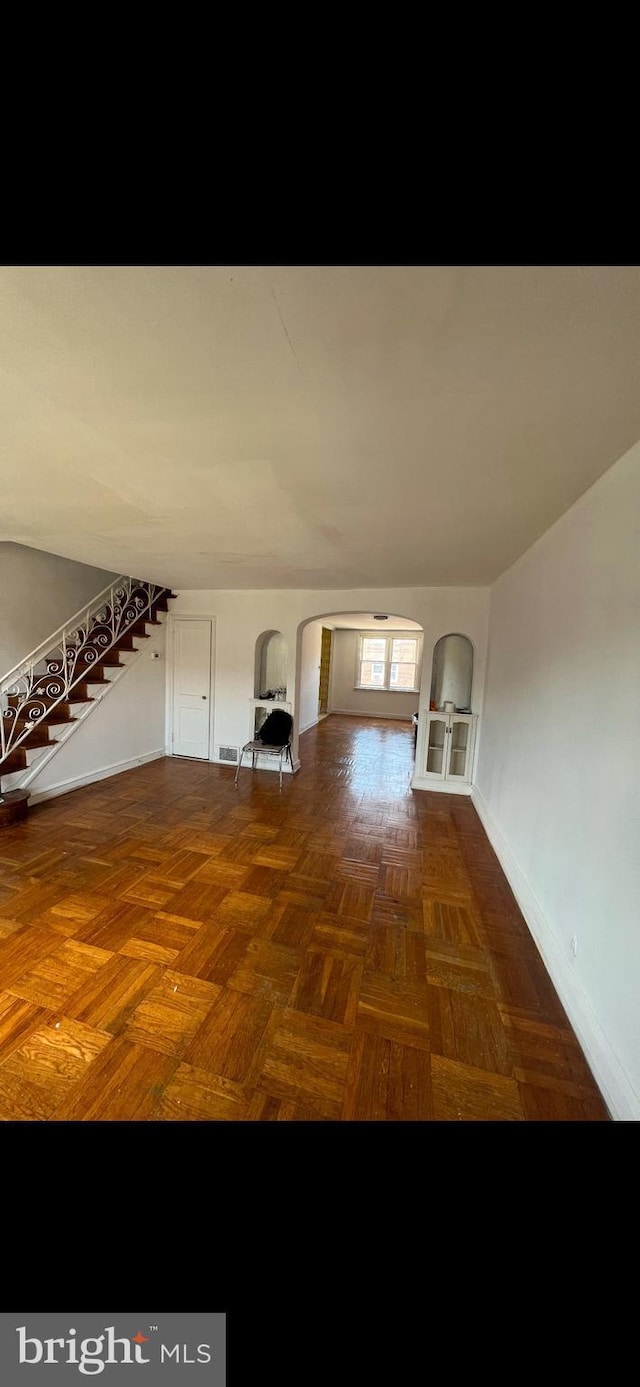 unfurnished living room featuring dark parquet floors