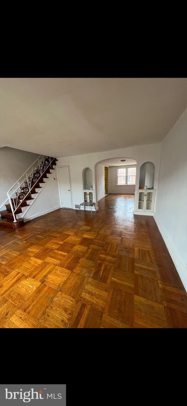 unfurnished living room featuring dark parquet floors