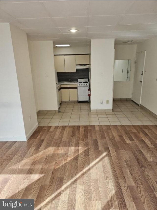 kitchen featuring light tile patterned floors, white electric range, sink, and white cabinets