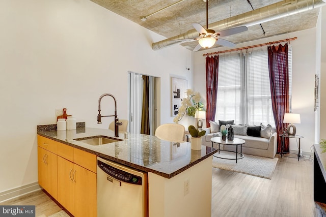 kitchen featuring stainless steel dishwasher, kitchen peninsula, dark stone counters, and sink