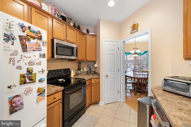 kitchen with black electric range oven, light tile patterned floors, fridge, a notable chandelier, and decorative light fixtures