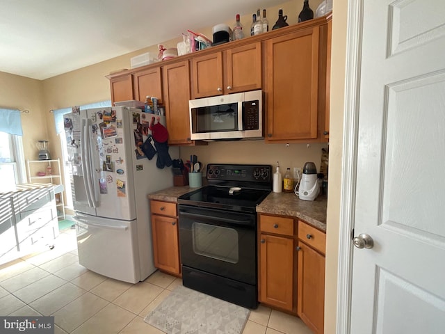 kitchen with white refrigerator, black electric range, and light tile patterned floors