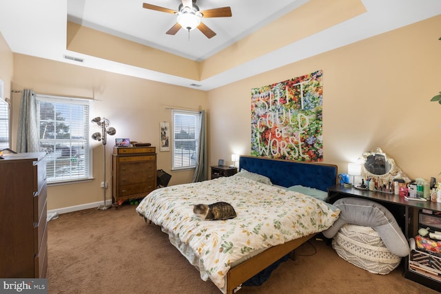 carpeted bedroom featuring a tray ceiling and ceiling fan