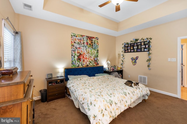 carpeted bedroom with a tray ceiling and ceiling fan