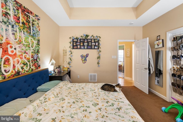 bedroom featuring dark carpet and a raised ceiling