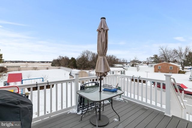 snow covered deck with a shed and grilling area