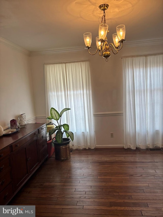 dining space featuring ornamental molding, dark wood-type flooring, and an inviting chandelier