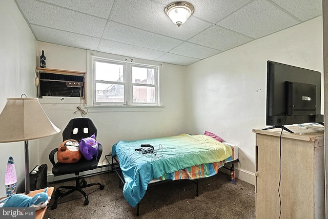 carpeted bedroom with baseboards, a paneled ceiling, and a wall unit AC