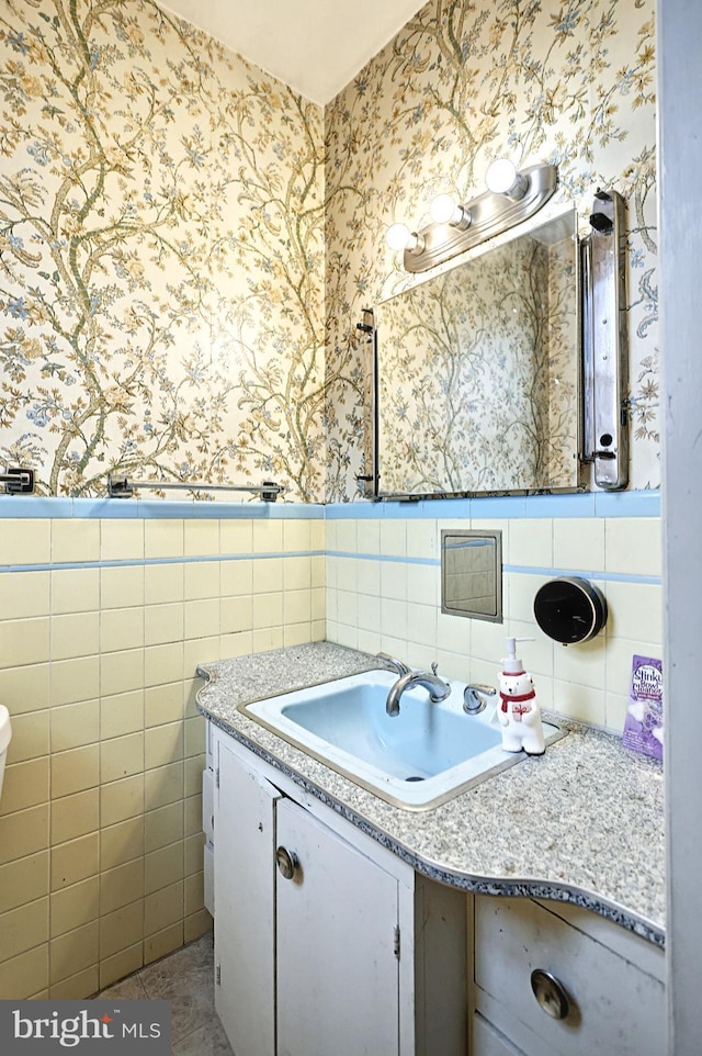 bathroom featuring wallpapered walls, tile walls, a wainscoted wall, and vanity