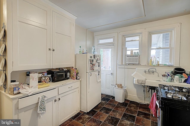kitchen with stone finish flooring, white cabinetry, light countertops, and freestanding refrigerator