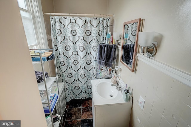 bathroom featuring curtained shower, stone finish flooring, and vanity