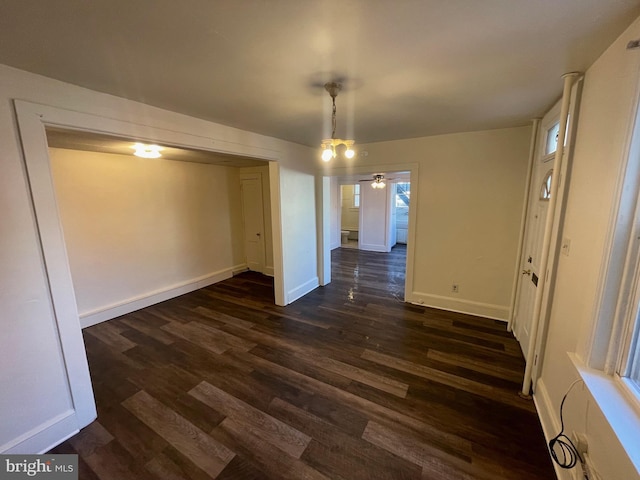 unfurnished dining area featuring a ceiling fan, baseboards, and dark wood-style flooring