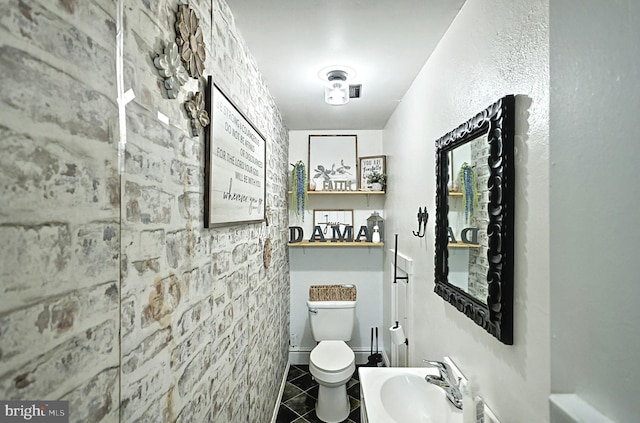 bathroom featuring toilet, tile patterned floors, and a sink