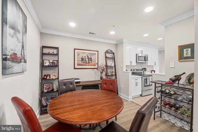 dining area featuring light hardwood / wood-style flooring and crown molding