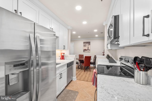 kitchen featuring light tile patterned floors, white cabinets, ornamental molding, stainless steel appliances, and light stone counters