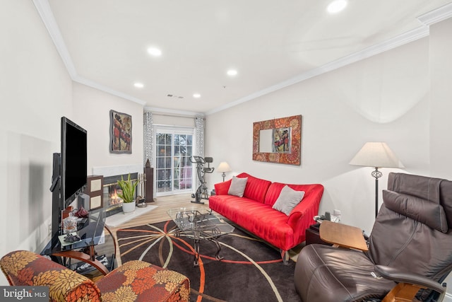 living room featuring a tiled fireplace, ornamental molding, and wood-type flooring