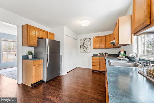 kitchen with a wealth of natural light, sink, dark wood-type flooring, and stainless steel refrigerator