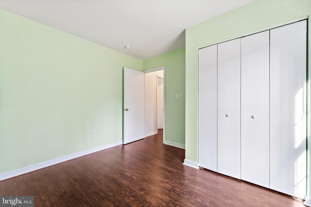 unfurnished bedroom featuring dark hardwood / wood-style flooring and a closet