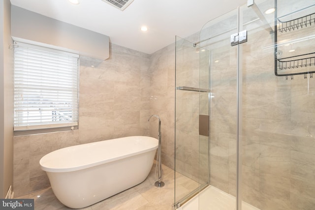 bathroom with tile walls and independent shower and bath