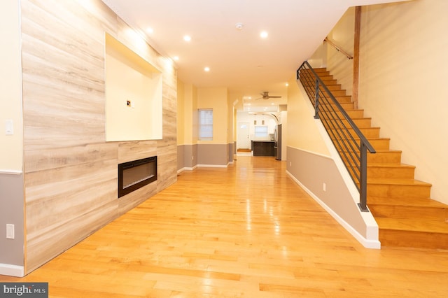 unfurnished living room featuring ceiling fan, hardwood / wood-style floors, and a tiled fireplace