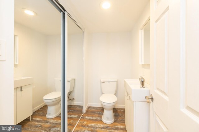 bathroom with toilet, vanity, and hardwood / wood-style floors