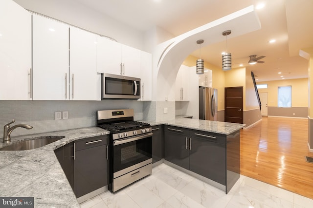 kitchen featuring pendant lighting, sink, appliances with stainless steel finishes, white cabinets, and light stone counters