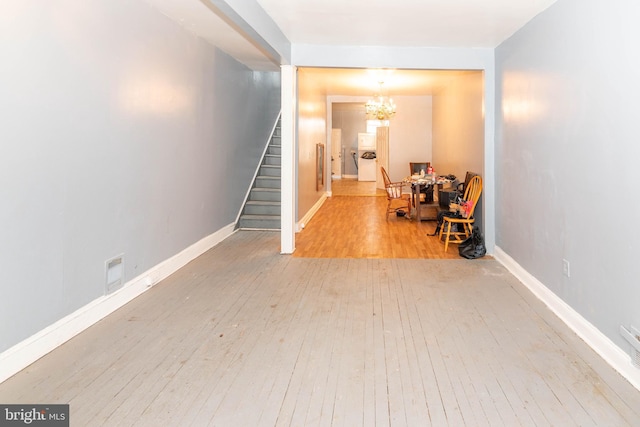 hallway with light wood-type flooring and a notable chandelier