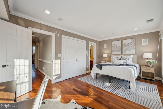 bedroom featuring a closet, ensuite bath, ornamental molding, and wood-type flooring