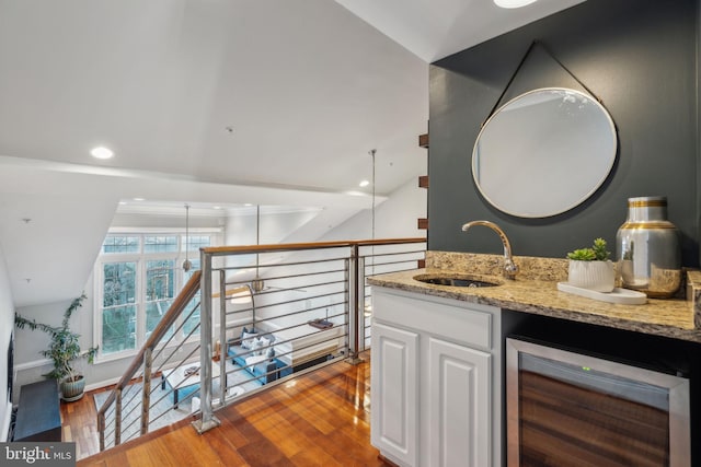 interior space with sink, vaulted ceiling, wine cooler, and hardwood / wood-style flooring