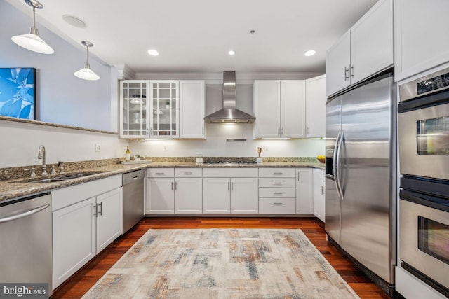 kitchen featuring wall chimney exhaust hood, sink, white cabinets, light stone countertops, and stainless steel appliances