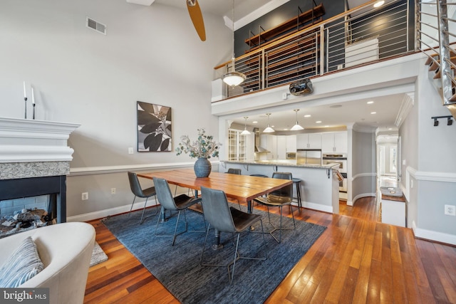 dining space featuring hardwood / wood-style flooring, a high ceiling, and ornamental molding