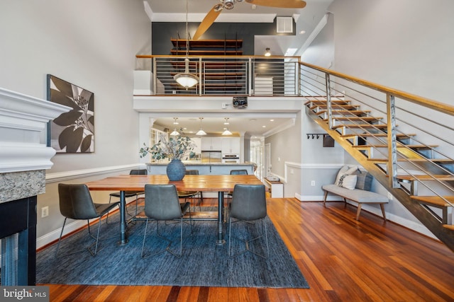 dining room featuring a high ceiling, wood-type flooring, and ornamental molding